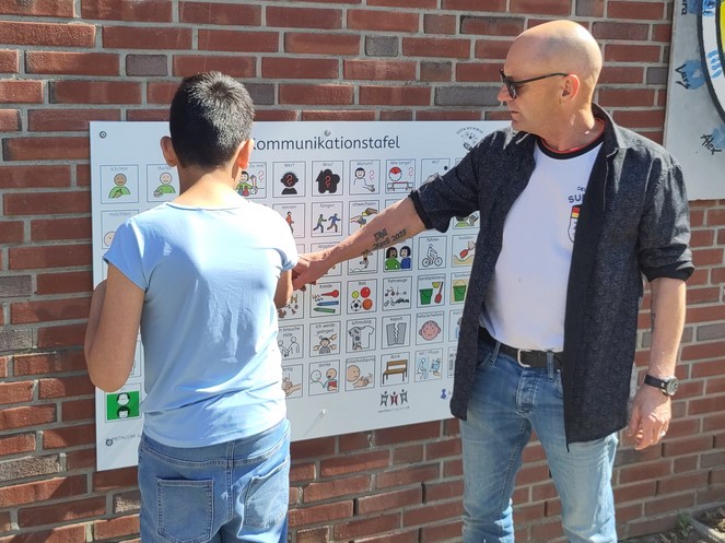 Ein Schüler und ein Helfer erkunden die Kommunikationstafel